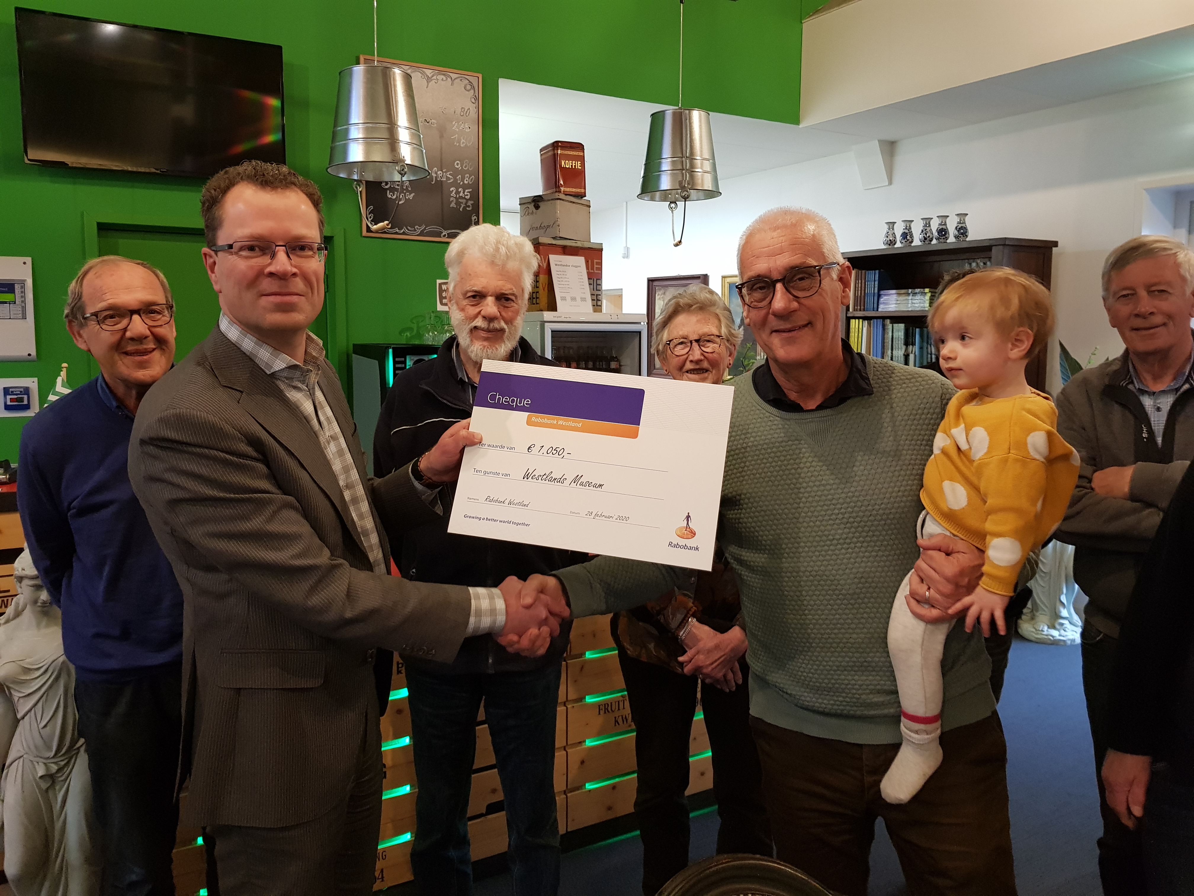 Dennis Zielstra (2e van links) overhandigt de cheque aan voorzitter Jan Prins (3e van rechts)